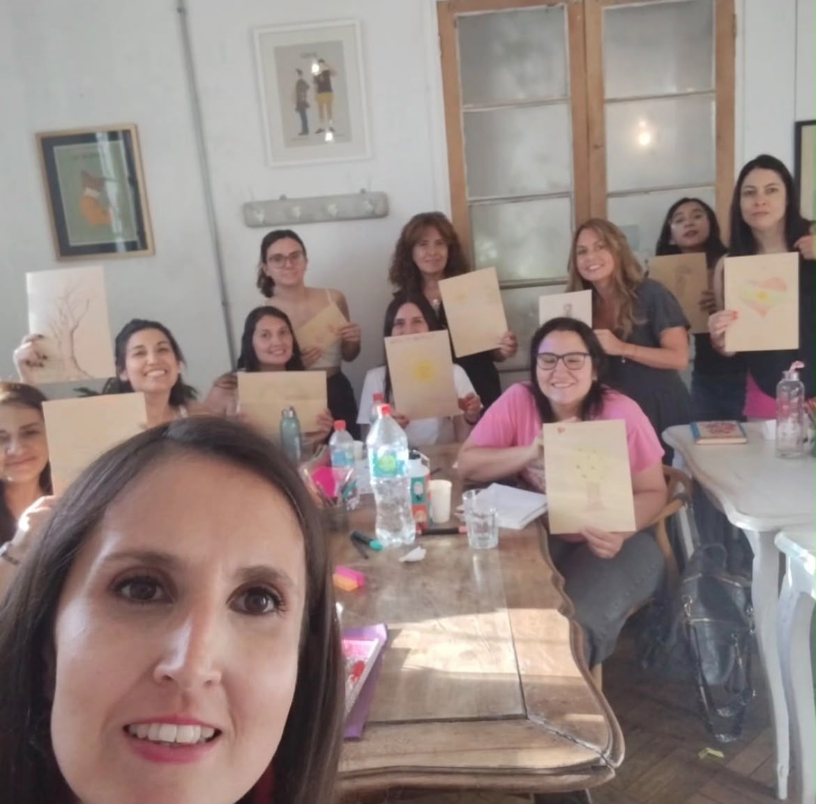 Violeta Urzúa junto a un grupo de mujeres en un taller, mostrando dibujos que hicieron durante la sesión